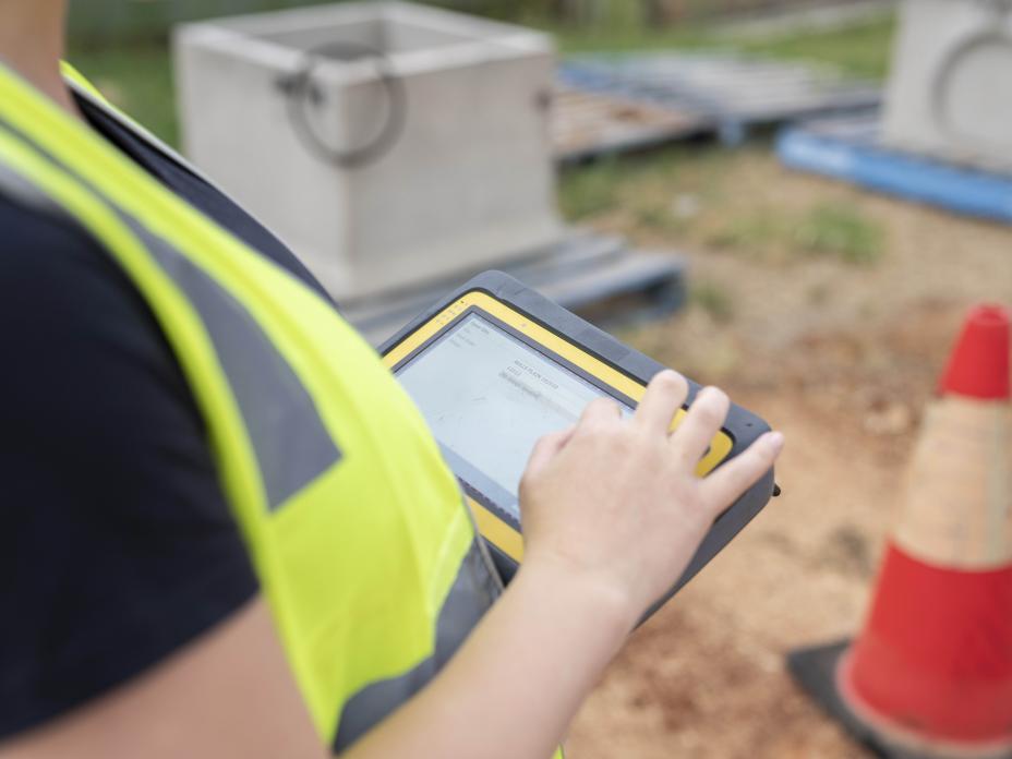 Female on housing construction site, with device, close up