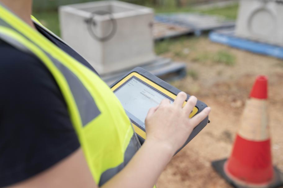 Female on housing construction site, with device, close up