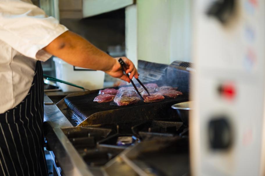 Male chef frying steaks