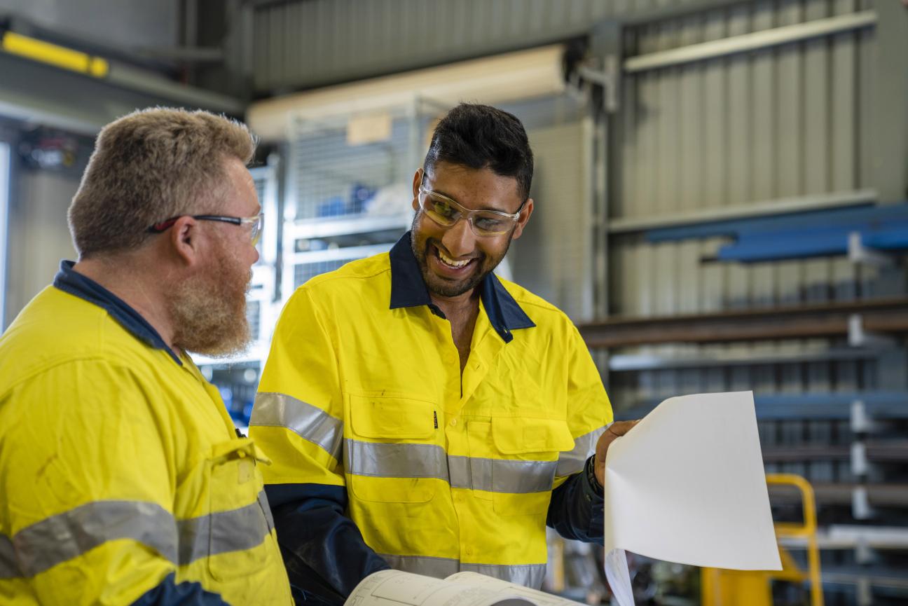 Males on construction site with layouts, mid shot